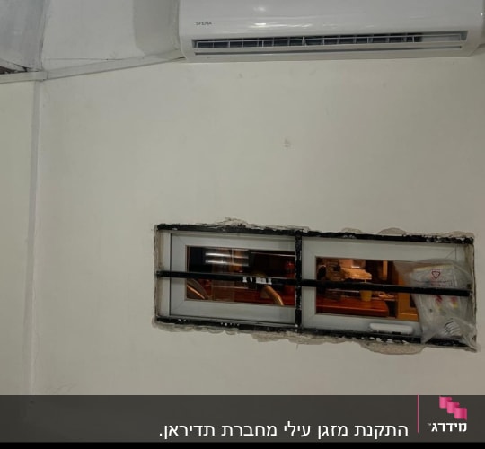 מזגן מותקן על קיר לבן עם תצוגת טמפרטורה